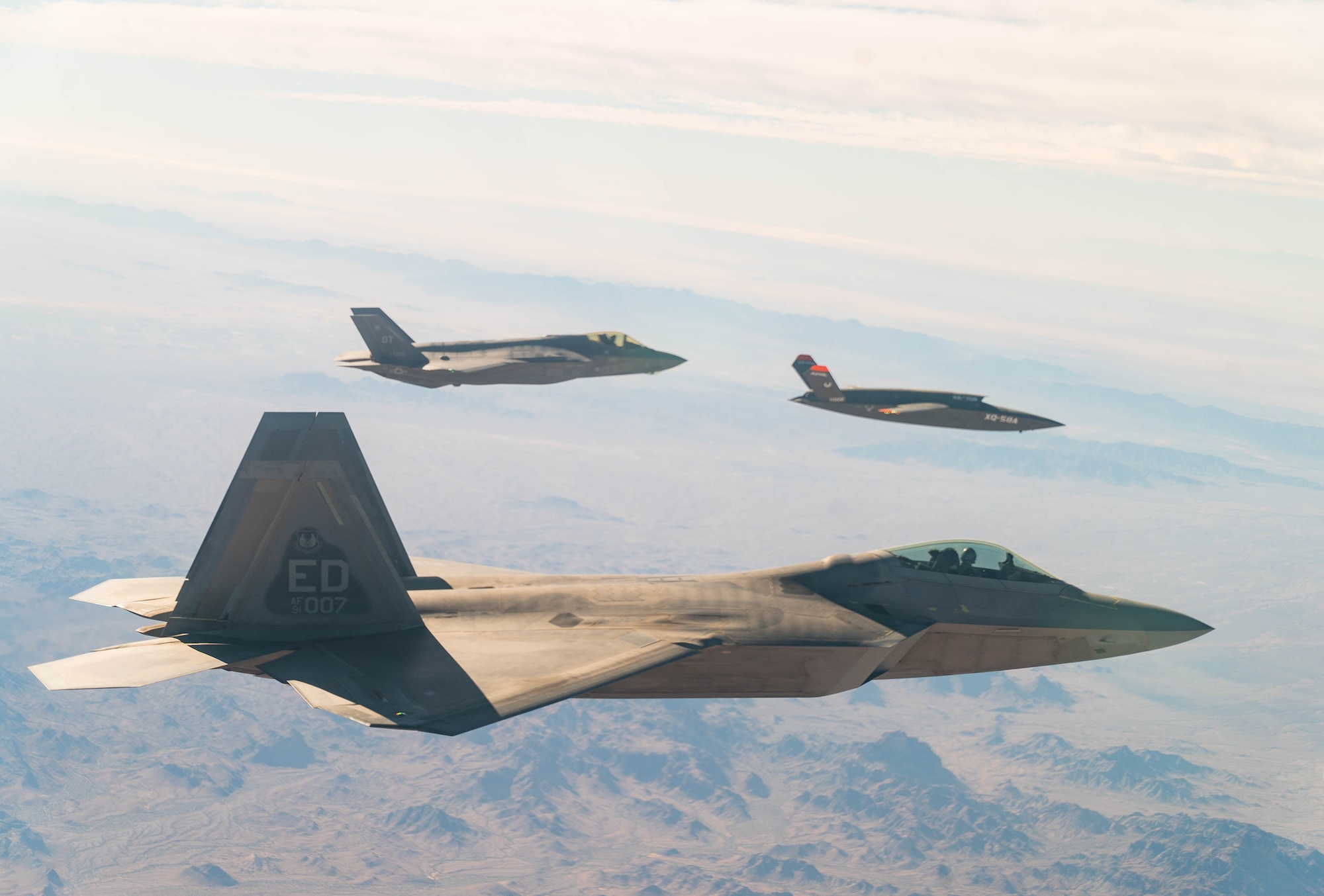 A U.S. Air Force F-22 Raptor and F-35A Lightning II fly in formation with the XQ-58A Valkyrie low-cost unmanned aerial vehicle over the U.S. Army Yuma Proving Ground testing range, Ariz., during a series of tests Dec. 9, 2020. This integrated test follows a series of gatewayONE ground tests that began during the inaugural Department of the Air Force on-ramp last year in December.