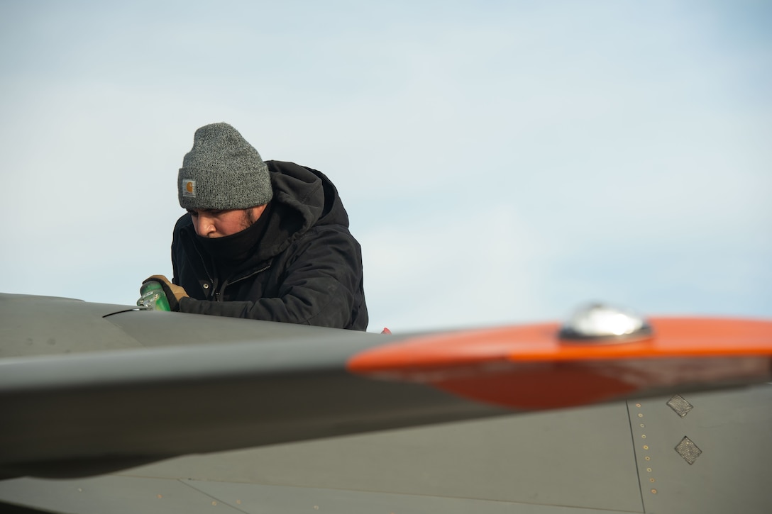 An XQ-58A Valkyrie maintainer pours fuel into the aircraft on a launchpad at the U.S. Army Yuma Proving Ground, Ariz., Dec. 9, 2020. More than 50 team members came together to make the historic flight a safe event. The joint effort included a Marine Corps F-35B variant, an Air Force F-22 Raptor, and an Air Force F-35A variant. The Air Force F-22 and F-35A aircraft flew with the attritableONE platform for the first time.