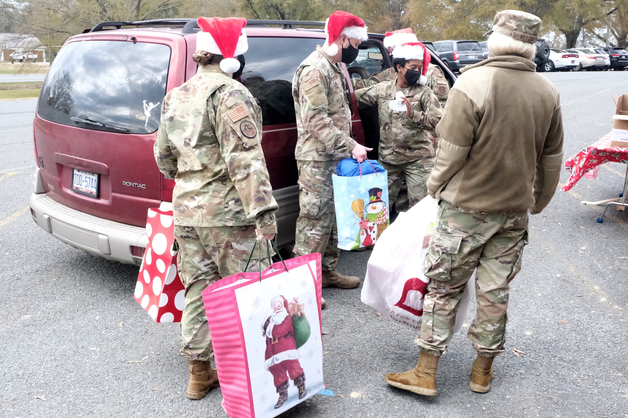 Members of the North Carolina Air National Guard assist with loading presents and food into a vehicle during Operation Santa Claus held at Oakboro Elementary School in Oakboro, N.C. Dec. 13, 2020. The Chapter 7 organization within the North Carolina Air National Guard hosts the Annual Operation Santa Claus event as a way to reach out to the community and spread holiday cheer and spirit. Chapter 7 and volunteers passed out nearly 100 boxes of food donated by the local Food Lion as well as 50 presents designated to students within the school.