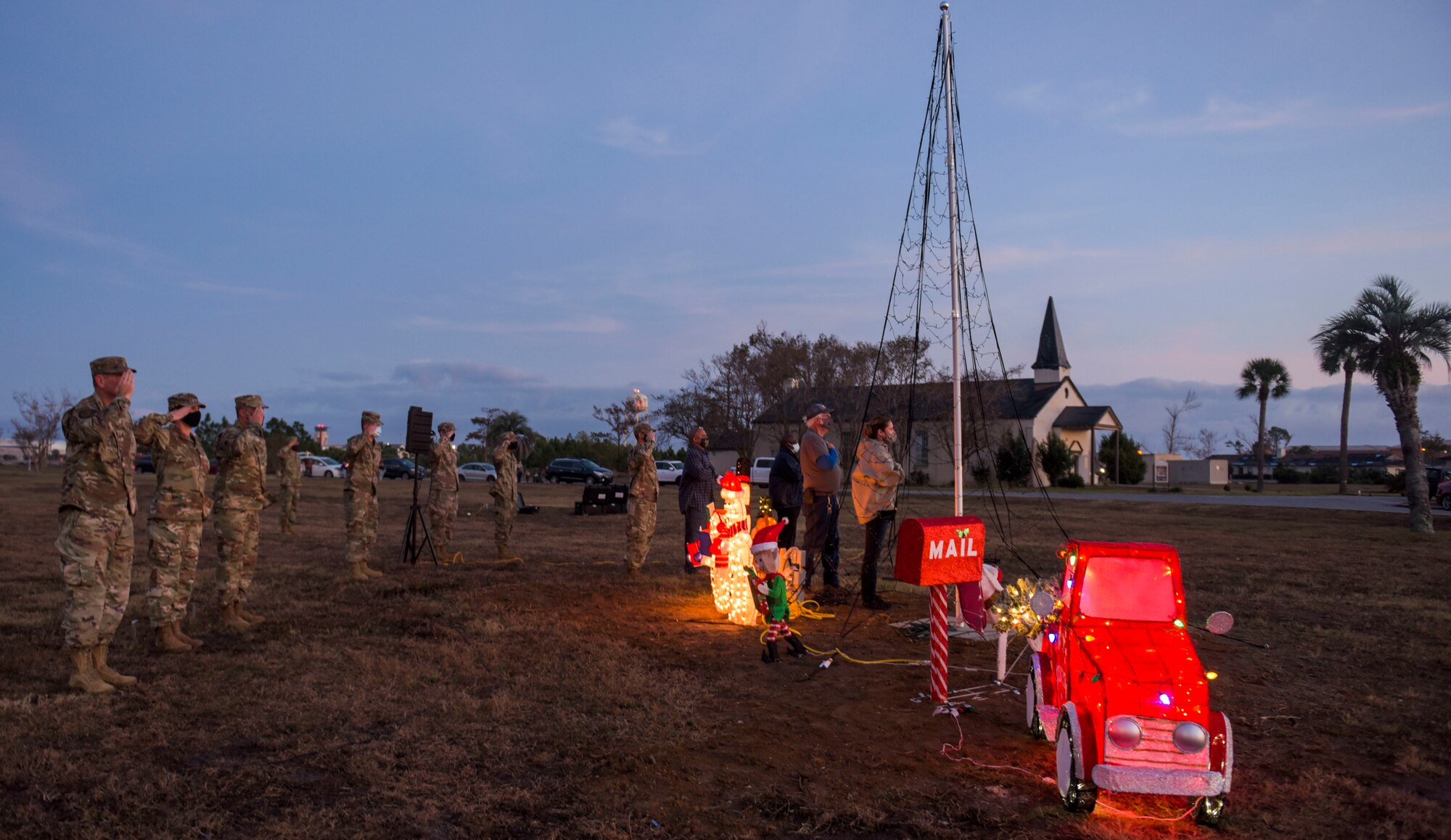 From left to right; U.S. Air Force Col. Gregory Beaulieu, 325th Mission Support Group commander,  Chief Master Sgt. Kati Grabham, 325th Fighter Wing command chief, and Col. Chris Peters, 325th FW vice commander, join Airmen, civilians and their families saluting the American flag at Tyndall Air Force Base, Florida, Dec. 4, 2020. The National Anthem is played over a base-wide intercom system signaling the end of the duty day and uniformed members must render a salute. (U.S. Air Force photo by Staff Sgt. Magen M. Reeves)