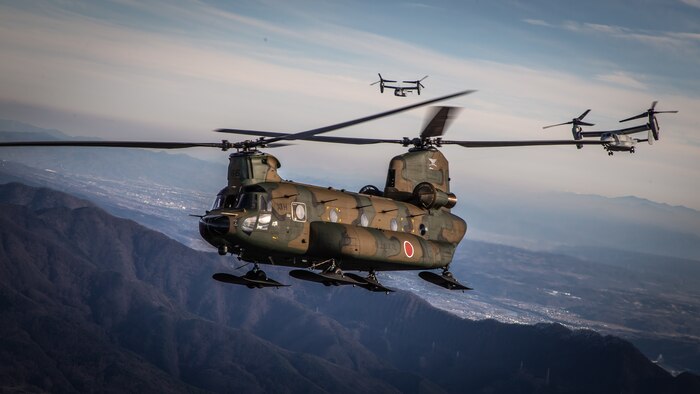 U.S. Marine Corps MV-22B Ospreys and a CH-47JA Chinook helicopter assigned to the Japan Ground Self Defense Force fly in a formation over the flight line at Camp Soumagahara, Japan, Dec. 9.