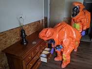 Sgt. Matt Giddens opens a dresser to discover whether it is contaminated as Staff Sgt. Dustin Foreman observes