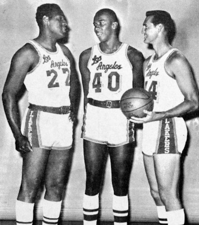 Three men wearing basketball uniforms with the words Los Angeles talk among themselves as they pose for a photo. One of the men holds a basketball.