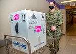 Hospital Corpsman 3rd Class Hannah May pushes a cart with the first Coronavirus (COVID-19) vaccination delivery at Naval Medical Center Portsmouth (NMCP) on Dec. 15.