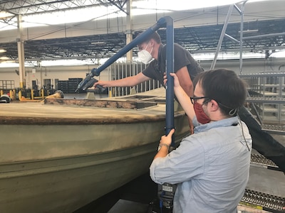 Naval Surface Warfare Center, Carderock Division engineers Ryan Fisher (bottom) and Ryan Evanko (top) use a FARO Arm 3D scanner to capture names carved into USS Saginaw’s surviving gig’s wooden hatch coamings.