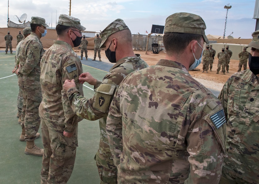 U.S. Soldiers of Alpha Company, 1st Battalion, 35th Armored Regiment, 2nd Heavy Brigade Combat Team, stand at attention to receive their shoulder sleeve insignia for former wartime service, commonly referred to as a combat patch, in a ceremony in Southwest Asia, Nov. 26, 2020