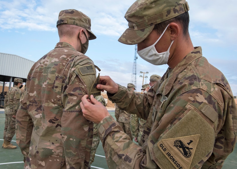 U.S. Soldiers of Alpha Company, 1st Battalion, 35th Armored Regiment, 2nd Heavy Brigade Combat Team, stand at attention to receive their shoulder sleeve insignia for former wartime service, commonly referred to as a combat patch, in a ceremony in Southwest Asia, Nov. 26, 2020.