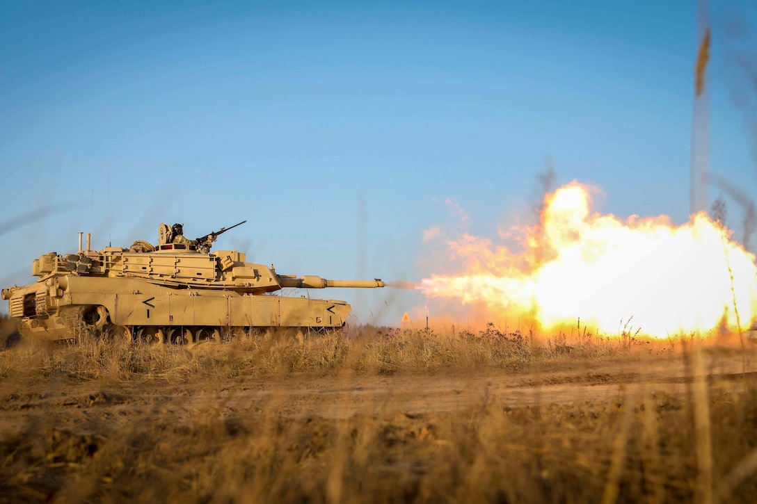 An Army tank fires in a field.