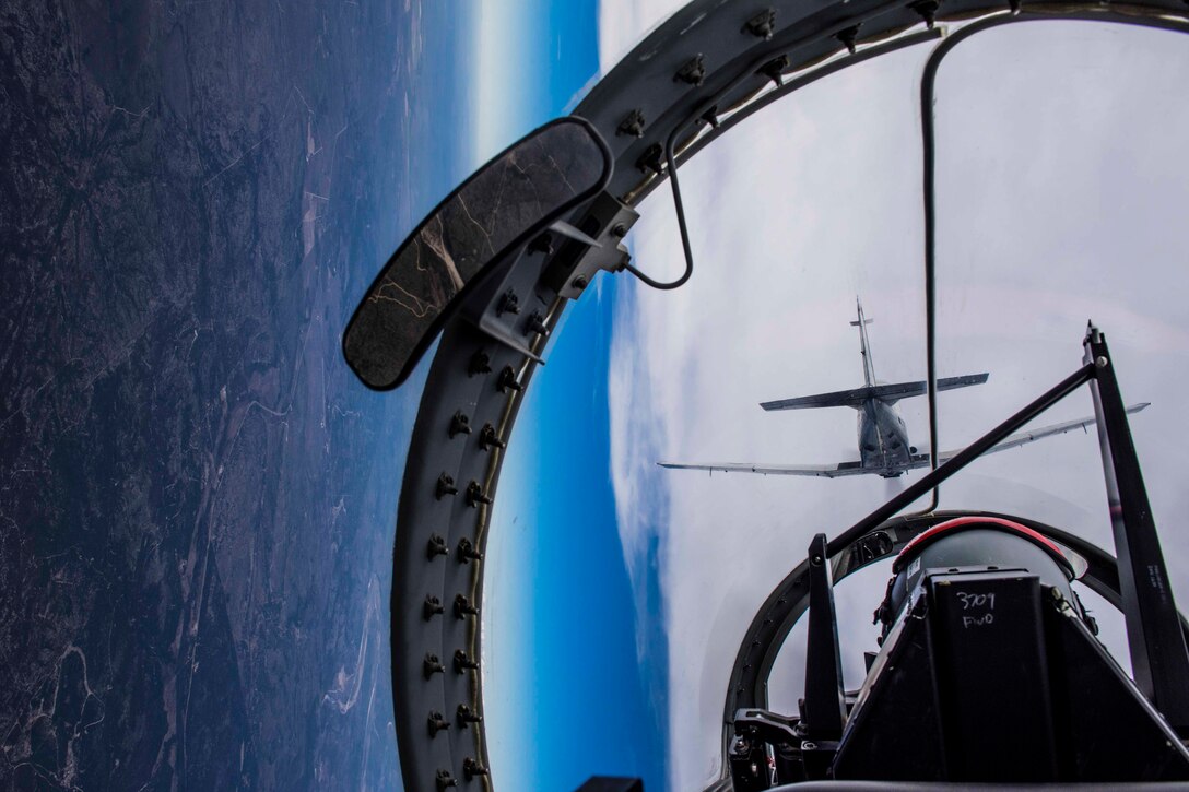 A view from inside a cockpit as a pilot flies an aircraft; another aircraft can be seen in front.