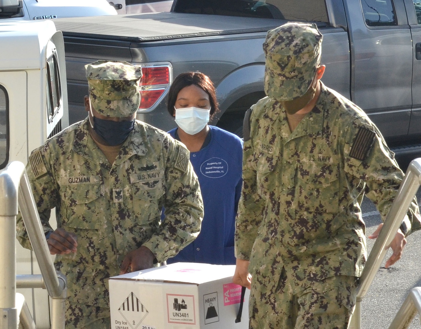 Sailors carry a container with COVID-19 vaccine at Naval Hospital Jacksonville.