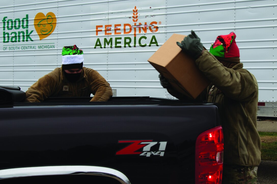 Two airmen help distribute food.