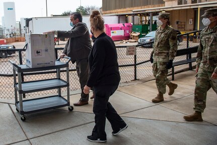 Spc. Martin Gamarra (far right) and Airman 1st Class Andreas Owen (center right) accompany medical professionals who will remove their allotment of COVID-19 vaccinations from their ultra-cold shipping container before resealing the container so the Guardsmen can continue their mission of delivering vaccines to sites across the state, Dec. 15, 2020.

Gamarra and Owen are part of a larger team of Guardsmen who are delivering vaccines from from one of five centralized hubs supporting 11 satellite locations across Oklahoma. The Guardsmen will be using Oklahoma State Department of Health vehicles to transport the vaccines to the satellite locations with an escort from the Oklahoma Highway Patrol. (Oklahoma National Guard photo by Anthony Jones)