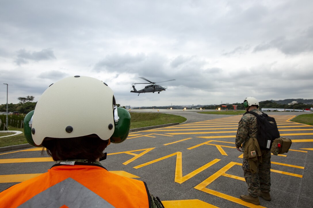 U.S. Sailors with Marine Aircraft Group (MAG) 36 and United States Naval Hospital Okinawa observe a U.S. Air Force HH-60G Pave Hawk helicopter landing during a joint search and rescue exercise at Camp Foster, Okinawa, Japan, Dec. 8, 2020. This exercise was conducted to improve understanding of the personnel recovery processes in Okinawa. (U.S. Marine Corps photo by Cpl. Ethan M. LeBlanc)