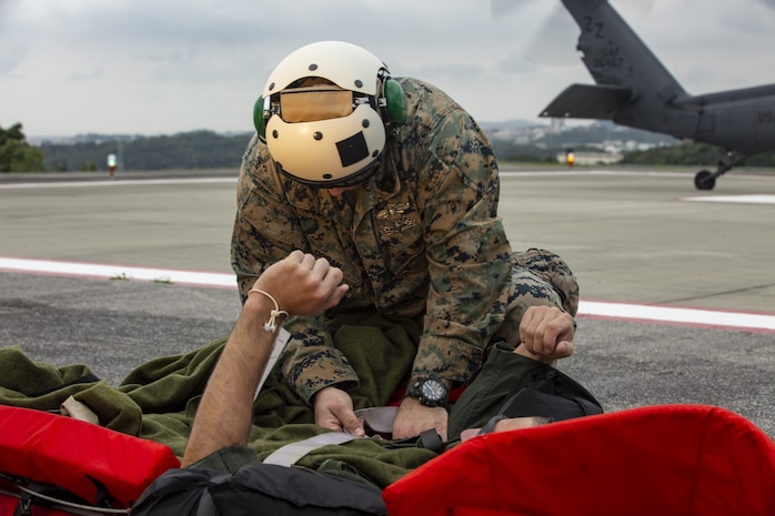 U.S. Navy Hospital Corpsman 2nd Class Patrick Doran, top, with Marine Aircraft Group (MAG) 36 begins treatment on a simulated casualty during a joint search and rescue exercise at Camp Foster, Okinawa, Japan, Dec. 8, 2020. This exercise was conducted to improve understanding of the personnel recovery processes in Okinawa. (U.S. Marine Corps photo by Cpl. Ethan M. LeBlanc)