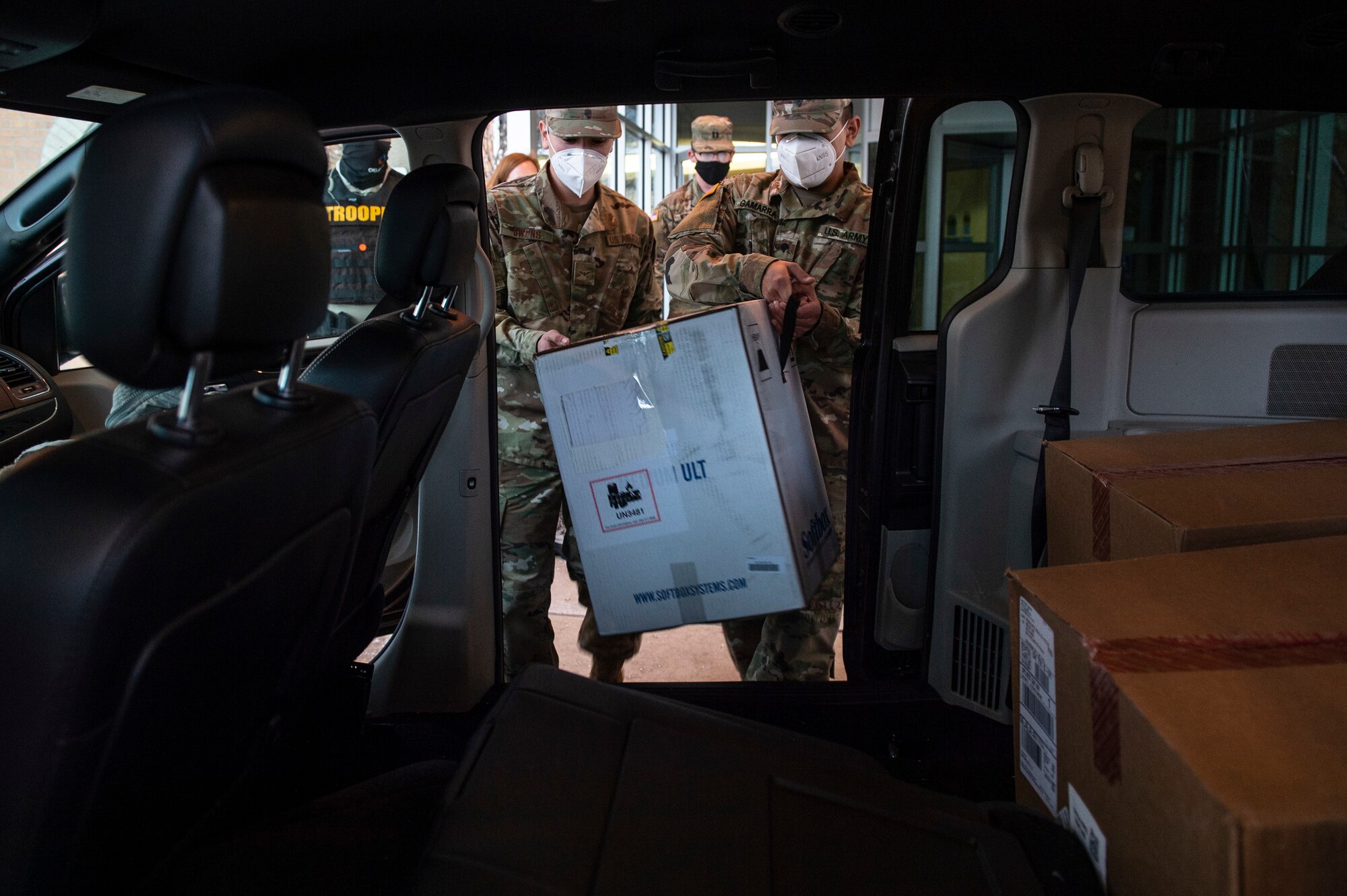 Spc. Martin Gamarra (right) and Airman 1st Class Andreas Owens (left) load a box containing COVID-19 vaccinations into  the vehicles the Guard members will use to transport the vaccines to sites across the state, Dec. 15, 2020.

On December 15, Guardsmen are transporting the first two boxes of vaccines to be distributed from one of five centralized hubs supporting 11 satellite locations across Oklahoma. The Guardsmen will be using Oklahoma State Department of Health vehicles to transport the vaccines to the satellite locations with an escort from the Oklahoma Highway Patrol. (Oklahoma National Guard photo by Anthony Jones)