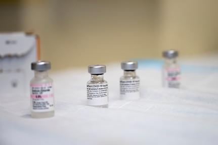 Doses of the COVID-19 vaccine sit in vials  on a table.