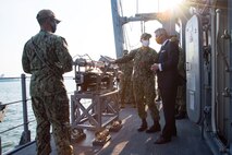 201215-N-IO414-1038 NAVAL SUPPORT ACTIVITY BAHRAIN (Dec. 15, 2020) Lt. Cmdr. Brent Holloway, commanding officer of the  mine countermeasure ship USS Devastator (MCM 6), speaks with Secretary of the Navy Kenneth J. Braithwaite about the capabilities of the ship during his visit with personnel on board U.S. Naval Support Activity Bahrain, Dec. 15. Devastator is deployed to the U.S. 5th Fleet area of operations in support of naval operations to ensure maritime stability in the Central Region, connecting the Mediterranean and Pacific through the Western Indian Ocean and three critical chokepoints to the free flow of global commerce.
