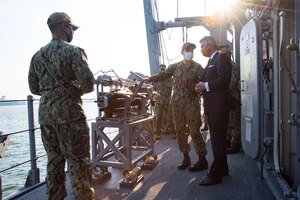 201215-N-IO414-1038 NAVAL SUPPORT ACTIVITY BAHRAIN (Dec. 15, 2020) Lt. Cmdr. Brent Holloway, commanding officer of the  mine countermeasure ship USS Devastator (MCM 6), speaks with Secretary of the Navy Kenneth J. Braithwaite about the capabilities of the ship during his visit with personnel on board U.S. Naval Support Activity Bahrain, Dec. 15. Devastator is deployed to the U.S. 5th Fleet area of operations in support of naval operations to ensure maritime stability in the Central Region, connecting the Mediterranean and Pacific through the Western Indian Ocean and three critical chokepoints to the free flow of global commerce.