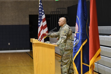 Col. Shahram A. Takmili stands behind podium and speaks to audience