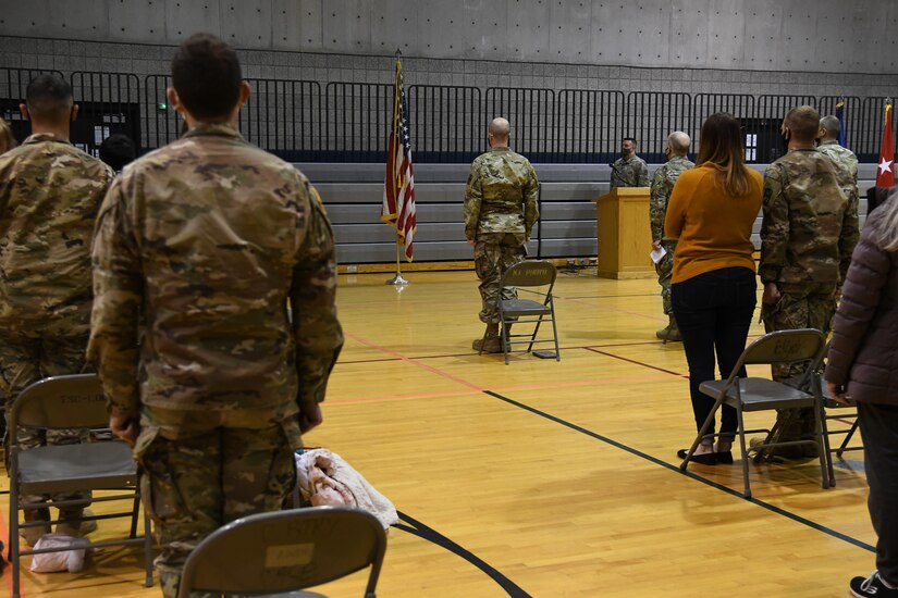 Soldiers and their families stand for the National Anthem.