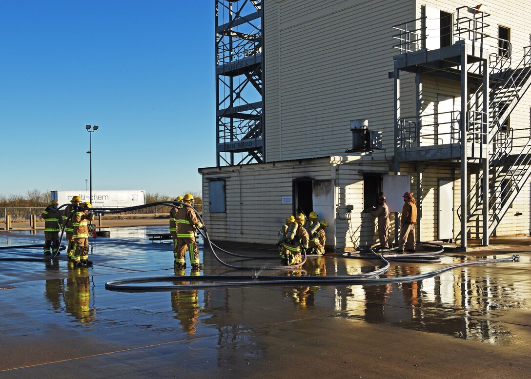 Department of Defense fire protection students from the 312th Training Squadron hustle to advantageous fire combating positions for the start of their grade level interior fire training exercise at the Louis F. Garland DOD Fire Academy on Goodfellow Air Force Base, Texas, Dec. 10, 2020. The students honed their fire retardant techniques in a controlled, yet life-like environment with real high-pressure fire hoses. (U.S. Air Force photo by Senior Airman Abbey Rieves)