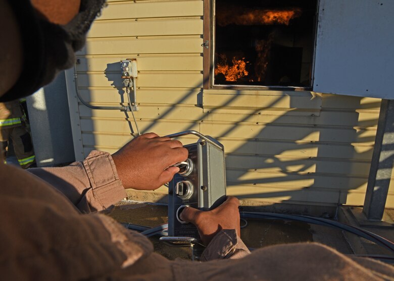 U.S. Army Staff Sgt. Ryan Clark, 312th Training Squadron fire protection instructor, cranks the controller igniting flames for the students during the grade level interior fire training exercise at the Louis F. Garland Department of Defense Fire Academy on Goodfellow Air Force Base, Texas, Dec. 10, 2020. As part of Goodfellow’s joint mission, instructors and students at the DOD fire academy trained in coalition across the enterprise.  (U.S. Air Force photo by Senior Airman Abbey Rieves)