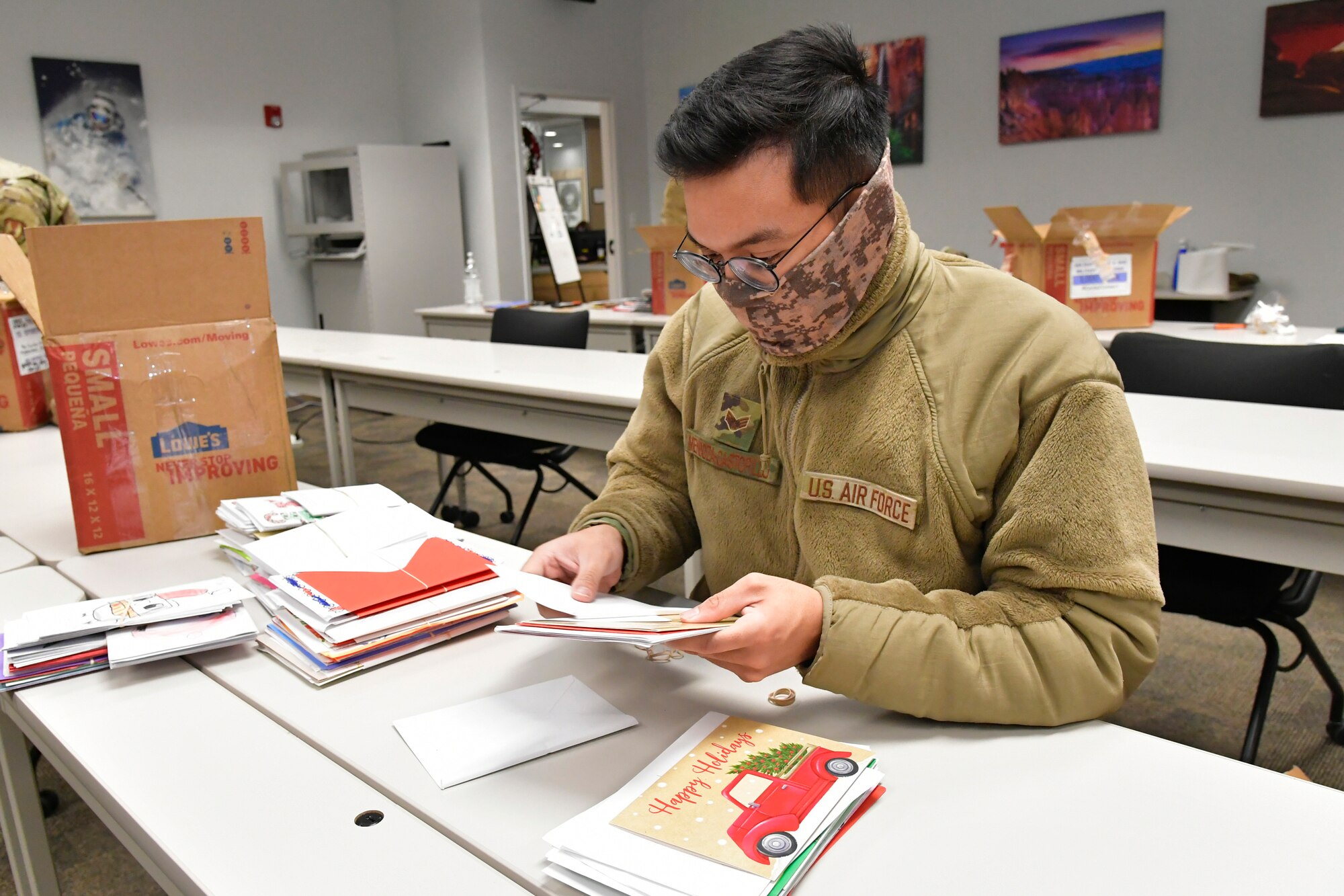 An Airman sorts holiday cards on a table.