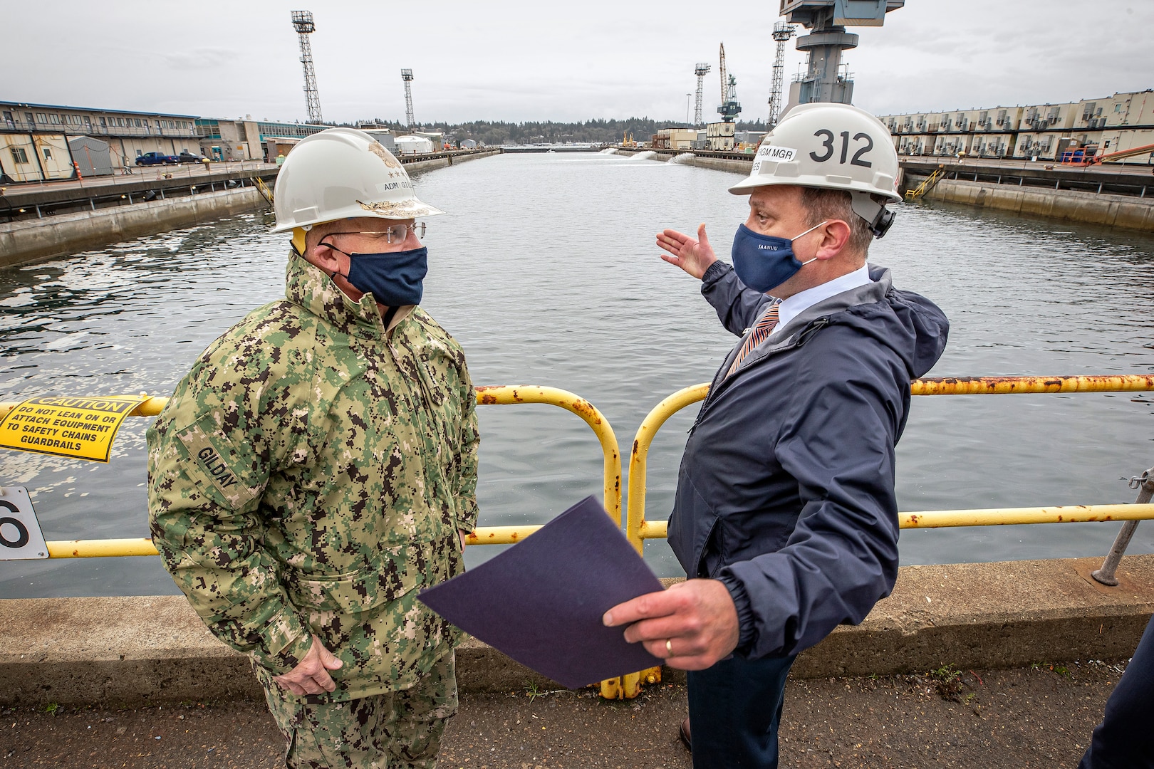 Chief of Naval Operations Adm. Mike Gilday discusses future Dry dock 6 seismic upgrades with Chris Hughes, Code 312, Carrier Program manager, Dec. 16, 2020, during Gilday’s tour of Puget Sound Naval Shipyard & Intermediate Maintenance Facility in Bremerton, Washington. (PSNS & IMF photo by Scott Hansen)