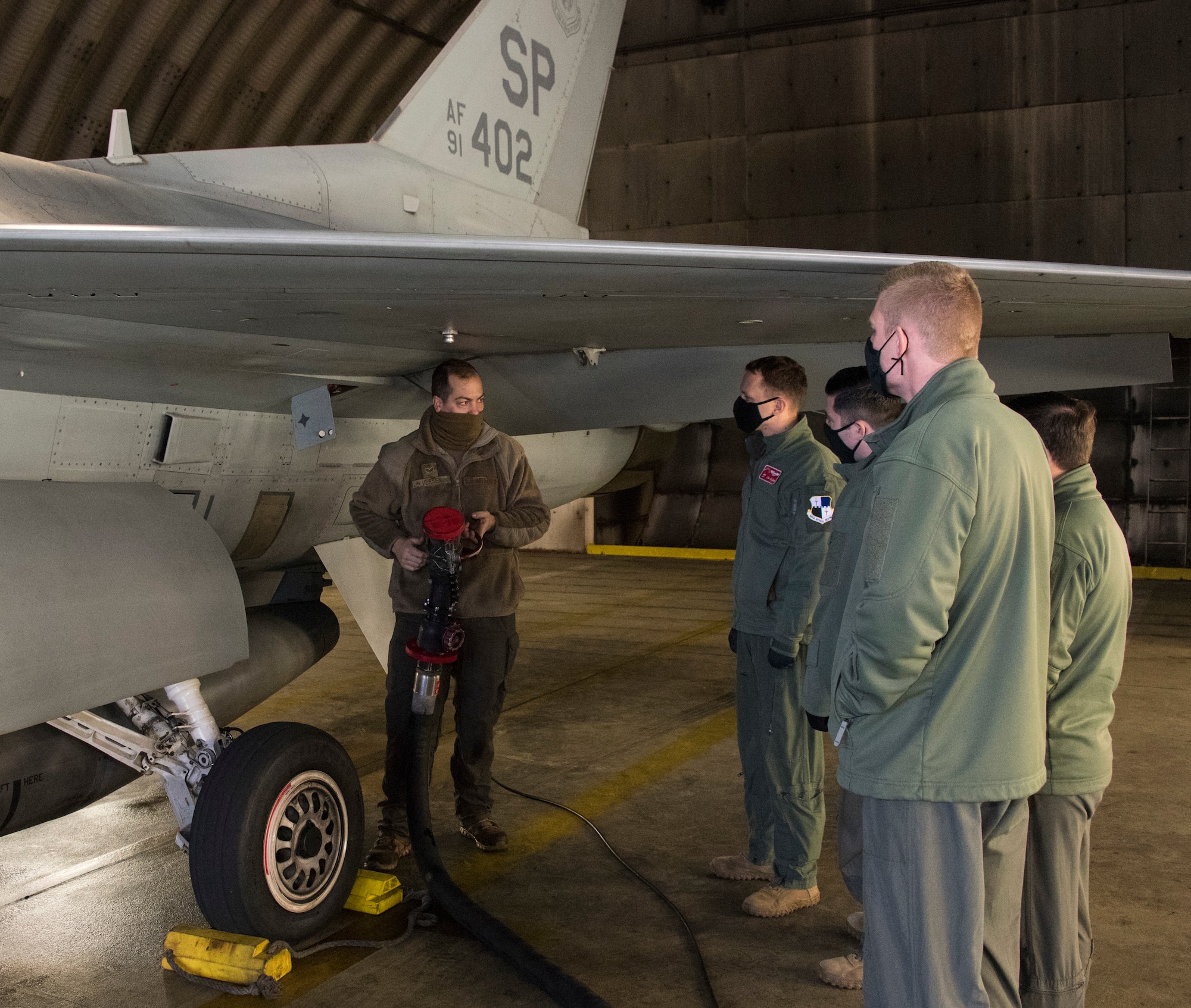 U.S. Air Force Senior Airman Ryan Versen, 52nd Aircraft Maintenance Squadron assistant dedicated crew chief, left, trains pilots how to refuel an F-16 Fighting Falcon at Spangdahlem Air Base Germany, Dec. 11, 2020. The training provided a hands-on experience for pilots on how to refuel a jet in case a crew chief is not present. (U.S. Air Force photo by Senior Airman Chance D. Nardone)