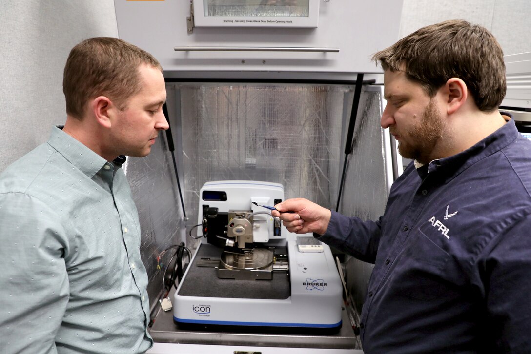 Dr. Nicholas Glavin, (left) research scientist at the Air Force Research Laboratory and David Moore, research scientist at UES, Inc. loading the sample into the analysis chamber. (U.S. Air Force photo/Spencer Deer)