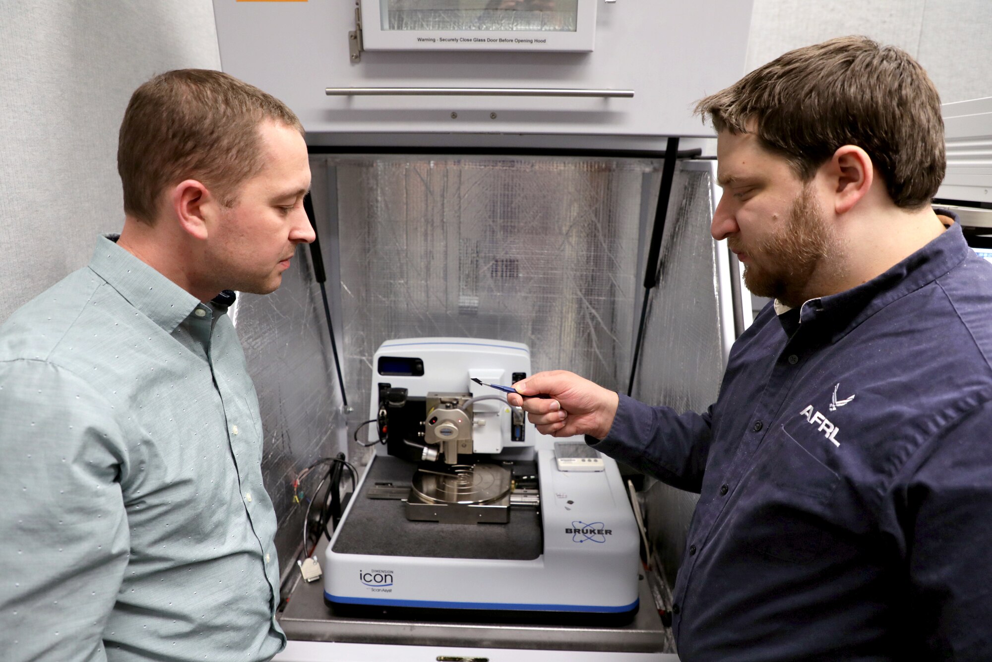Dr. Nicholas Glavin, (left) research scientist at the Air Force Research Laboratory and David Moore, research scientist at UES, Inc. loading the sample into the analysis chamber. (U.S. Air Force photo/Spencer Deer)