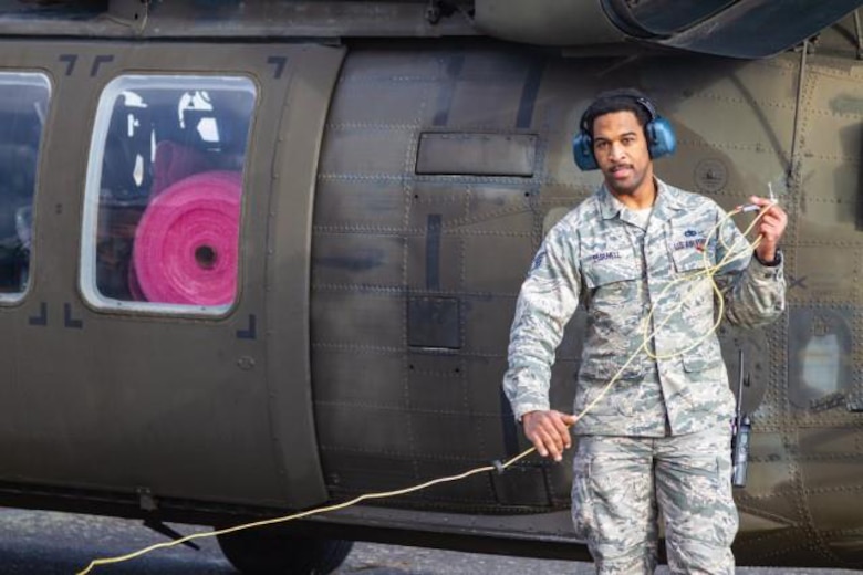 Airman standing in front of helicopter.