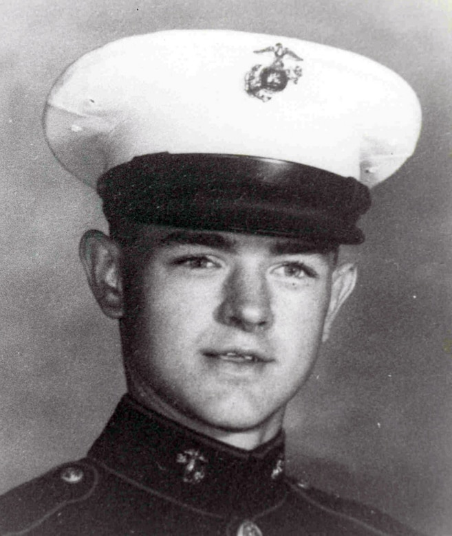 A man in a uniform and a cap looks at the camera.