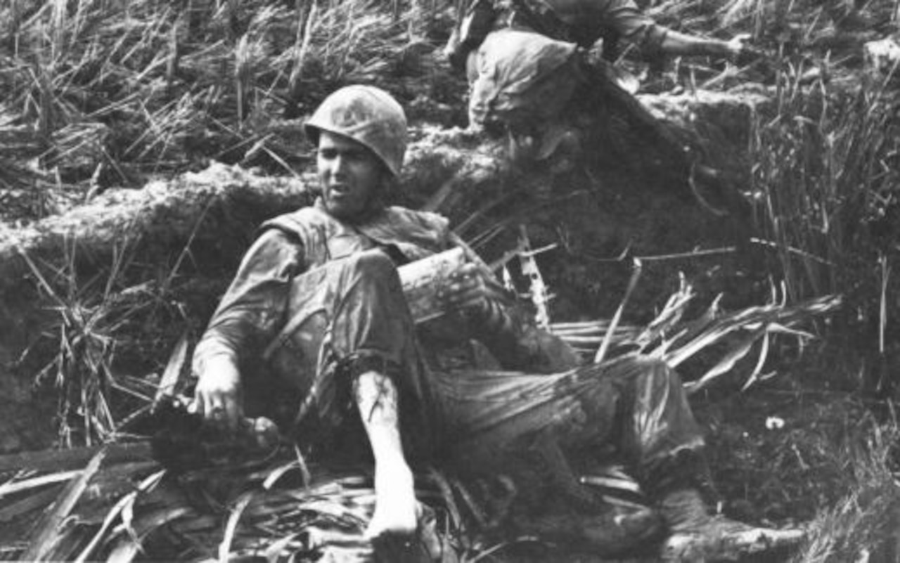 A man leans against the side of a dirt embankment.