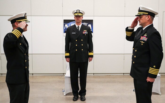 Rear Adm. Kevin Byrne, commander, NAVSEA Warfare Centers (center) looks on as Capt. Eric C. Correll (left) relieves Capt. Scott H. Kraft (right) as commanding officer of NSWC Indian Head Division on Dec. 16, during a change of command ceremony at the College of Southern Maryland’s Velocity Center in Indian Head, Maryland.