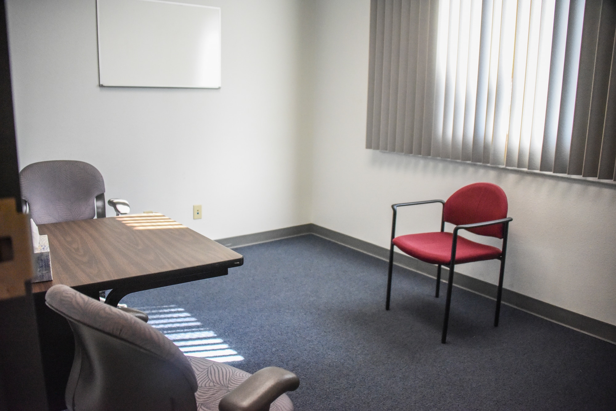 A picture of a small room with two grey chairs and one red chair.