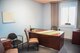 A picture of a blue room with worn furniture, and a desk in the middle.