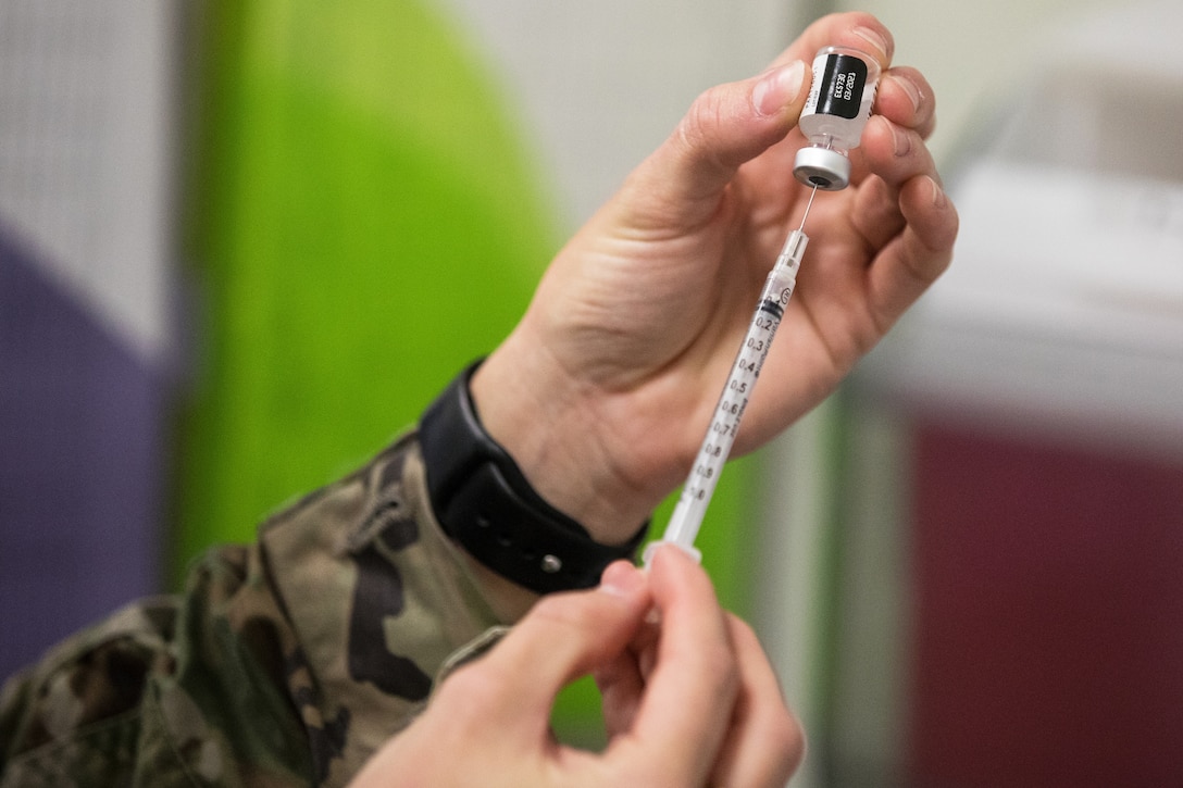 A soldier prepares a syringe of the COVID-19 vaccine.