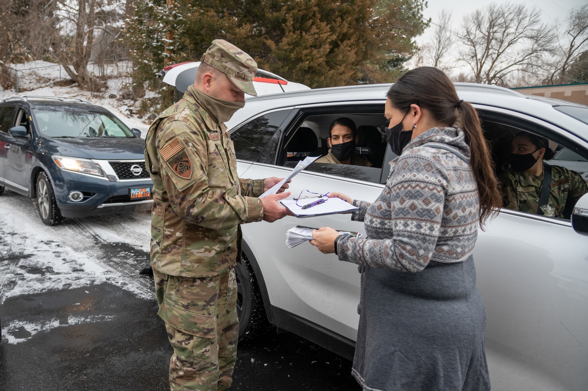 Master Sgt. Mikael Cunningham, 419th Fighter Wing, grabs a volunteer sign-up sheet from Amy Wicks, Lead Foster/Adoptive Consultant at Utah Foster Care Foundation in Ogden, Utah, Dec. 17, 2020, as part of a volunteer effort called Santa Brigade.