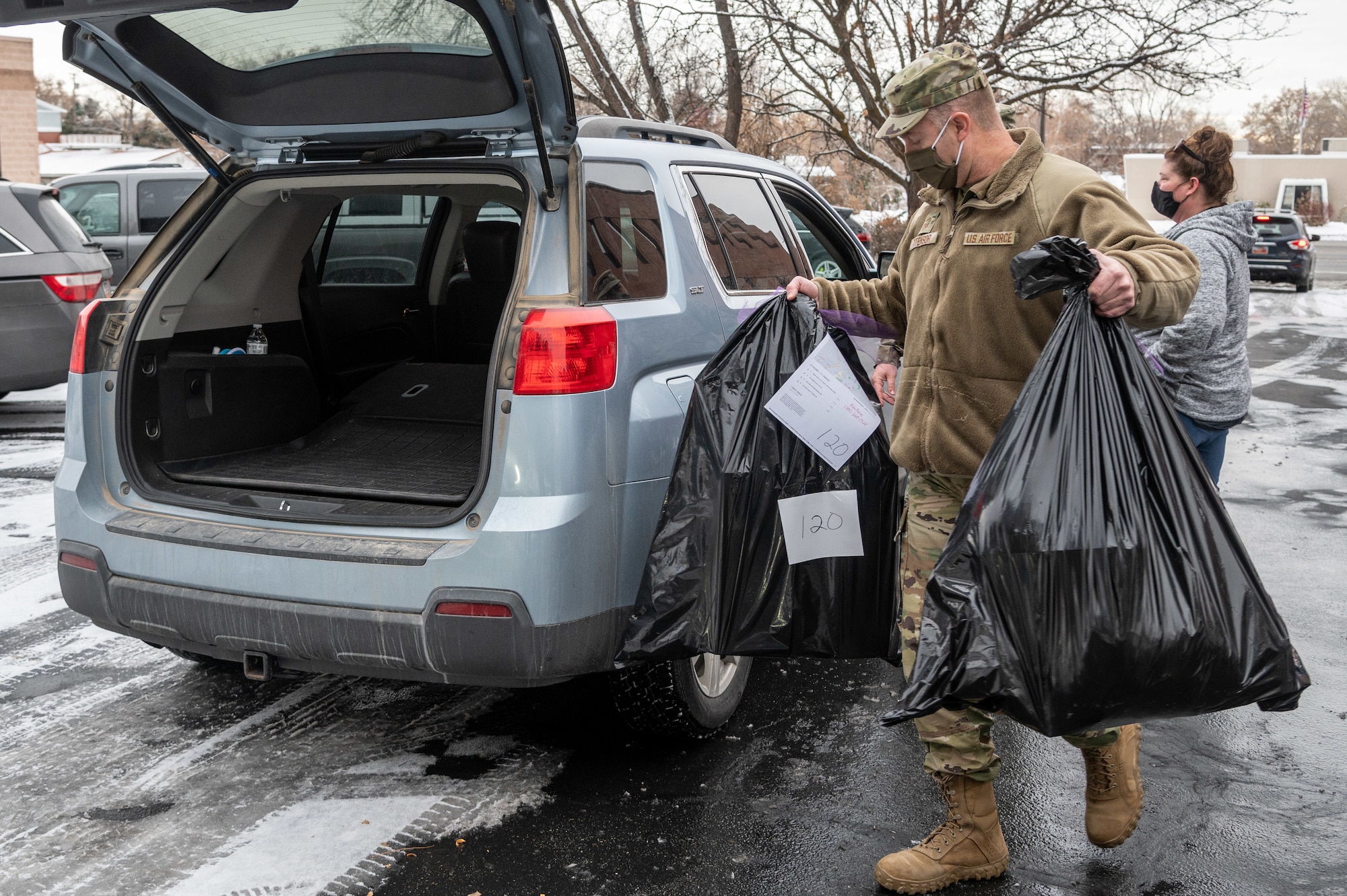 Senior Master Sgt. Drue Titensor, 419th Fighter Wing, loads bags of wrapped gifts into a volunteer's car at Utah Foster Care Foundation in Ogden, Utah, Dec. 17, 2020, as part of a volunteer effort called Santa Brigade