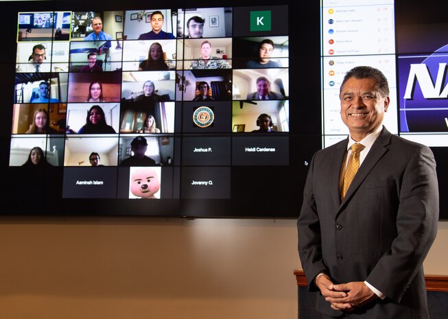 NSWC PHD Science, Technology, Engineering and Mathematics (STEM) Coordinator Ramon Flores in front of a screen with the Pre-Engineering Program graduates during a virtual graduation ceremony on Tuesday, Dec. 8. The 25 students from schools in the Oxnard Union High School District and Ventura Unified School District completed the program, which focused on naval STEM careers.