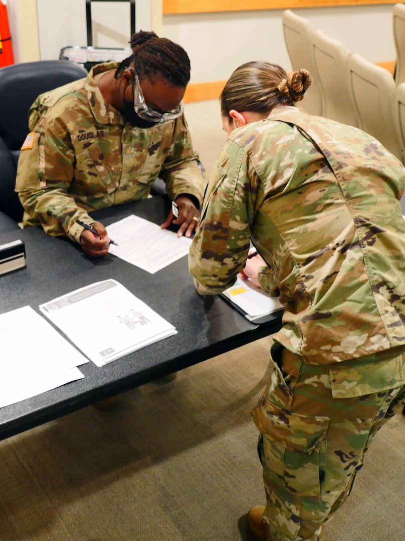 Army Maj. Sharon Douglas (left), chief of BAMC Pubic Health Nursing, screens Army Capt. Rebecca Parrish, a COVID-19 intensive care unit nurse, prior to Parrish’s COVID-19 vaccine administration Dec. 17 at Brooke Army Medical Center at Joint Base San Antonio-Fort Sam Houston. Parrish was the first BAMC staff member to receive a COVID-19 vaccine.