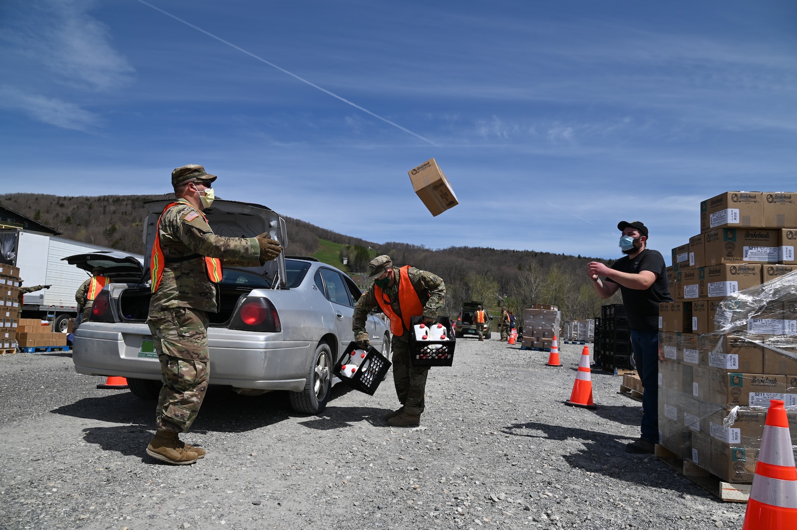 Vermont National Guard Soldiers and state partners load meals into vehicles in a parking lot in Peru, Vermont, May 19, 2020. The Vermont National Guard helps the Vermont Food Bank "Farmers to Families" program and Vermont Emergency Management deliver fresh produce, dairy and prepared meals. (U.S. Air National Guard photo by Tech. Sgt. Garth Dunkel)