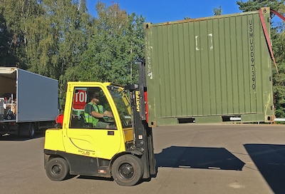 A material handling equipment operator unloads an item from a truck.