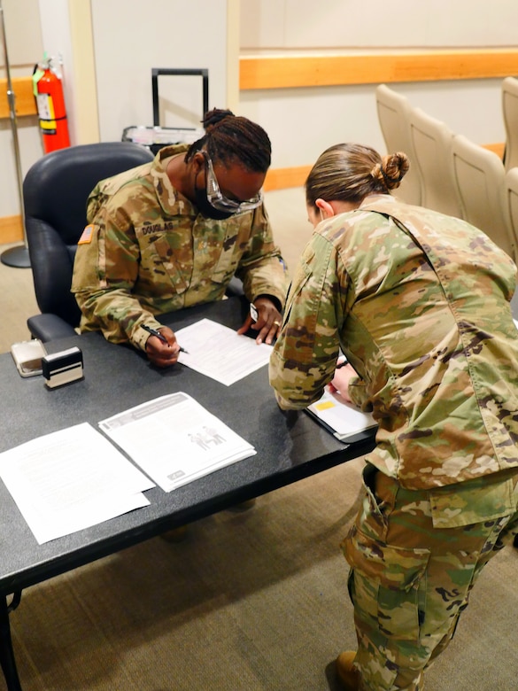 Soldiers complete paperwork on a desk.