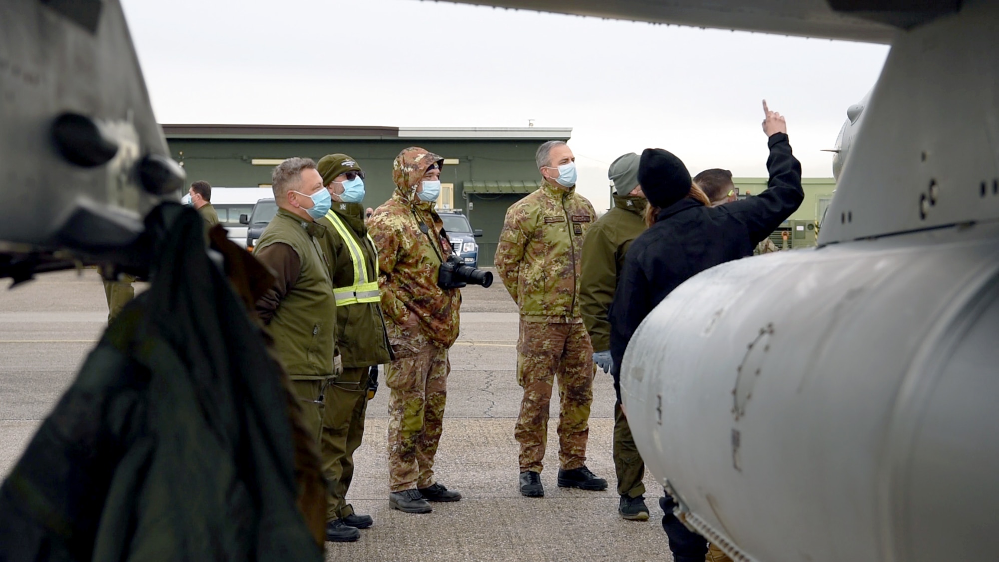 U.S. Air Force Staff Sgt. Kristina Bowers, 555th Aircraft Maintenance Unit crew chief, in black, briefs Italian air force members on the F-16 Fighting Falcon during a training exercise at Rivolto Air Base, Italy, Dec. 16, 2020. While there, the small contingent of U.S. Airmen trained their Italian counterparts on aspects of the F-16 such as handling munitions and manually opening the cockpit. (U.S. Air Force photo by Staff Sgt. Heidi Goodsell)