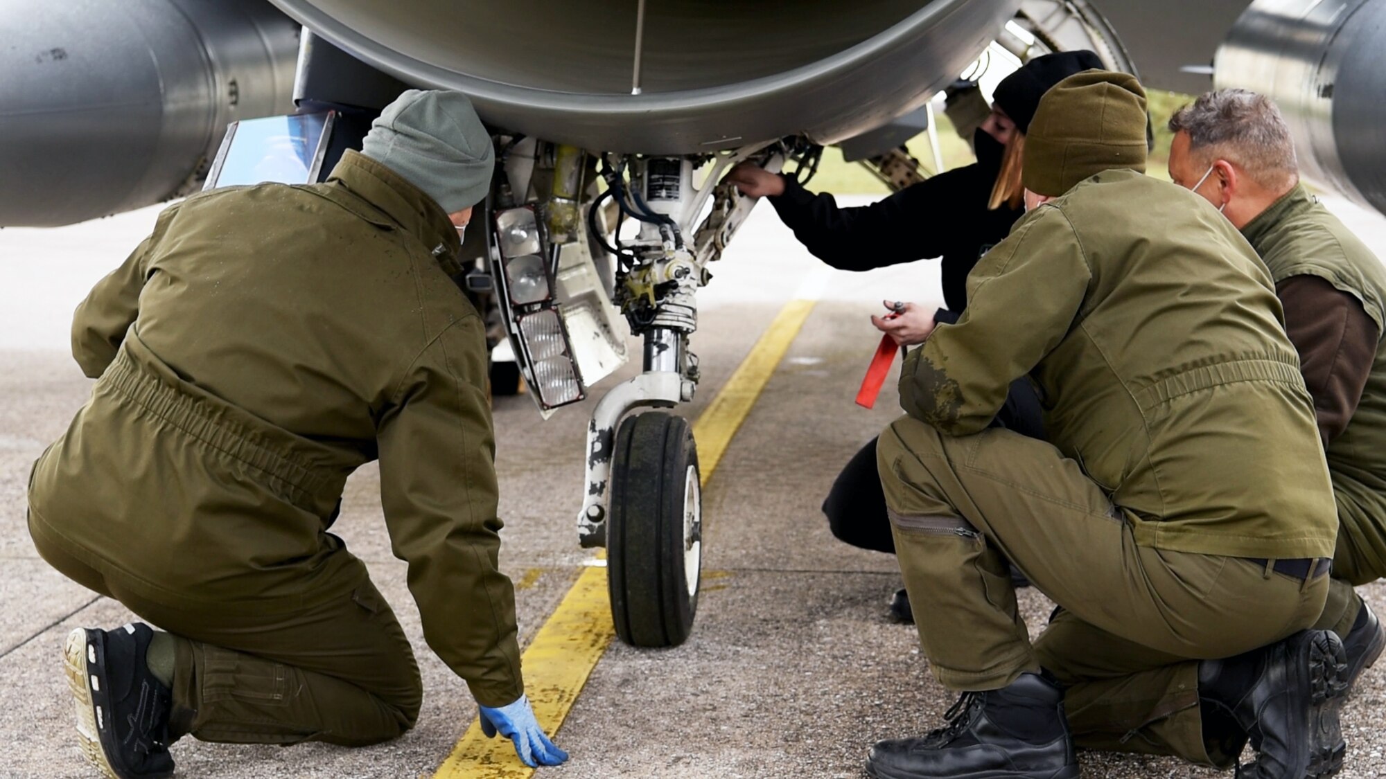 U.S. Air Force Staff Sgt. Kristina Bowers, 555th Aircraft Maintenance Unit crew chief, in black, briefs Italian air force members on the F-16 Fighting Falcon during a training exercise at Rivolto Air Base, Italy, Dec. 16, 2020. Airmen from the 31st Fighter Wing met two F-16s at Rivolto for the agile combat employment exercise, testing their ability to rapidly deploy and maneuver within a short time frame. (U.S. Air Force photo by Staff Sgt. Heidi Goodsell)