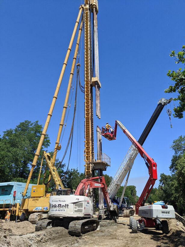 Construction crews install an additional section of augers to the deep mix method drill rig near Garcia Bend Park, in Sacramento’s Pocket neighborhood on June 2, 2020. Some sections of work require a seepage cutoff wall installed up to 130 feet deep, which is too deep for traditional long-stick excavation methods.