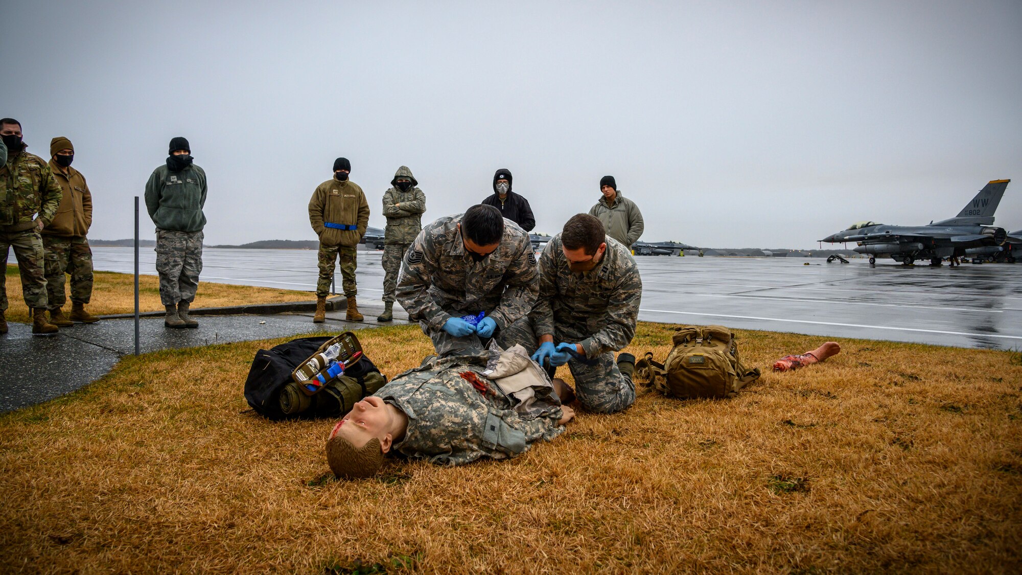 U.S. Air Force Airmen with the 35th Aircraft Maintenance Squadron watch the 14th Fighter Squadron individual duty medical technicians perform Tactical Combat Casualty Care (TCCC) training during Agile Combat Employment week at Misawa, Japan, Dec. 10, 2020. This training simulated a more realistic approach by using a mannequin with fake blood and injuries to assist in broadening the casualty care knowledge base of Airmen, enabling them to be capable of executing the mission across an expanded spectrum of mission-sets. (U.S. Air Force photo by Airman 1st Class China M. Shock)