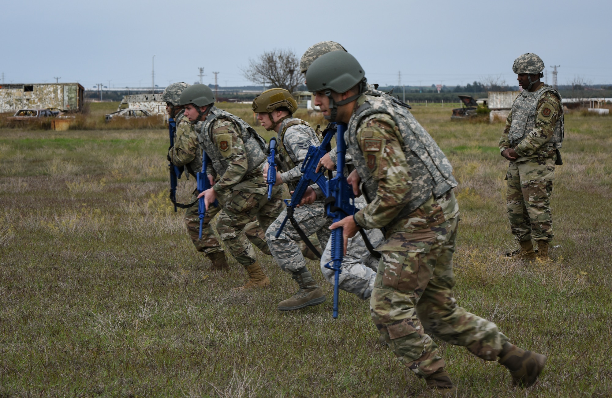 Airmen running with tactical gear in a field